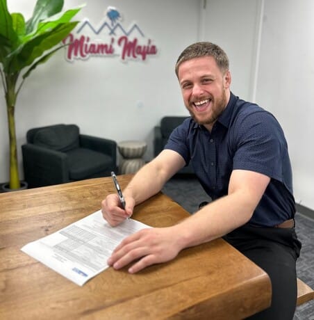 Person signing paperwork at Miami Mojo office